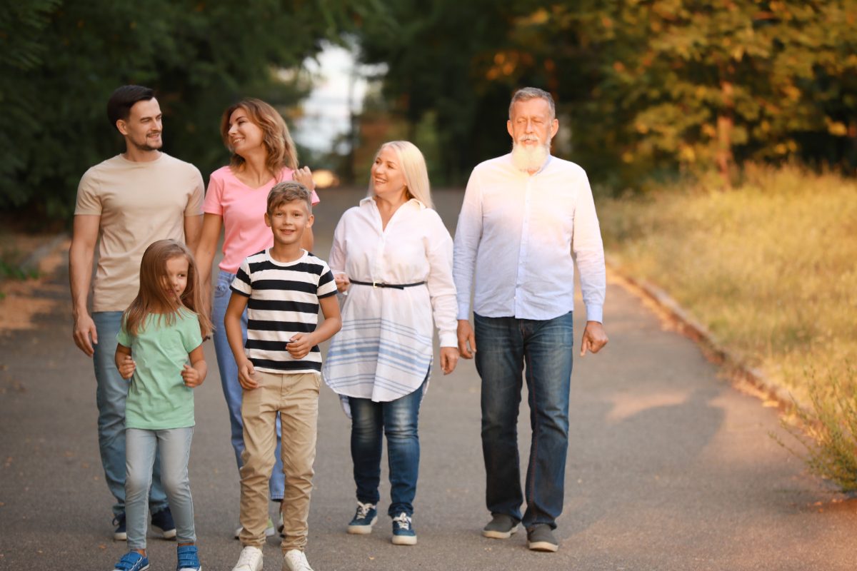 Three generations of a family walking together along a tree-lined path
